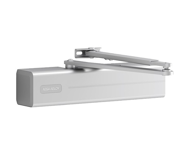 A close-up, eye-level shot of a silver Assa Abloy door closer. The rectangular main body is shown from the side with the brand name
